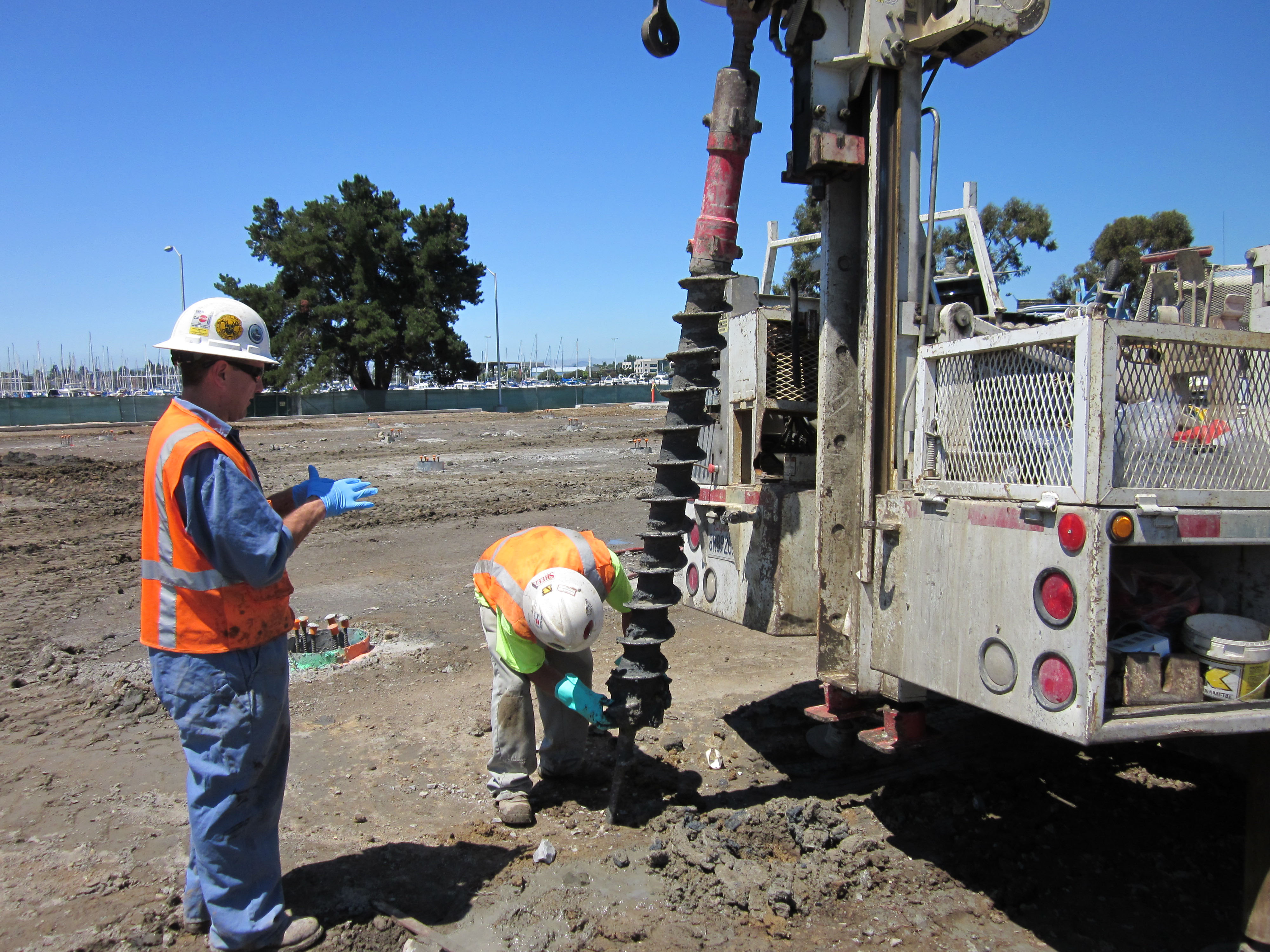 Photo of two workers operating a drill in a wooded area