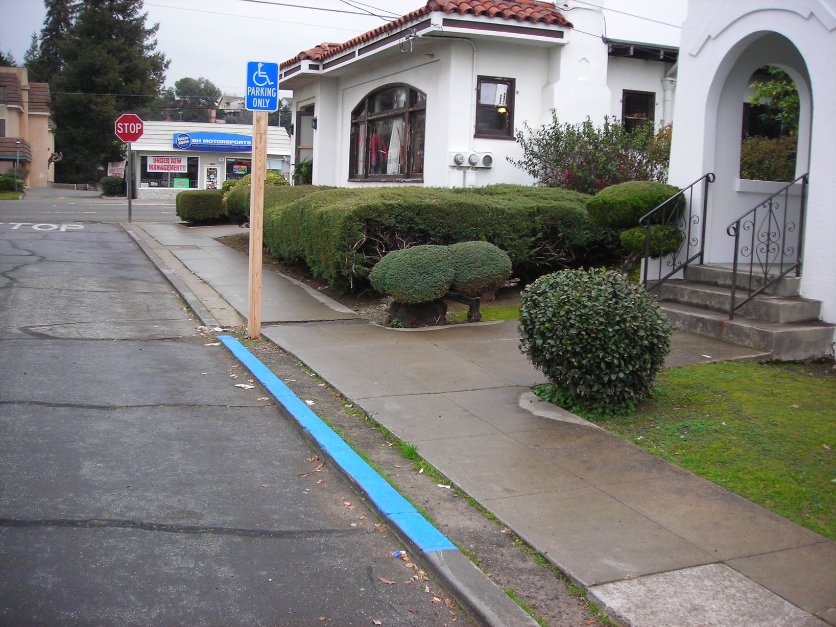 A photo of a residence with blue disabled parking zone and a disabled parking sign