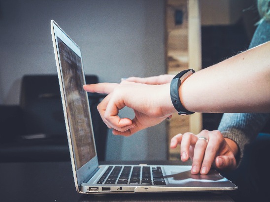 close up of a laptop and people pointing at screen