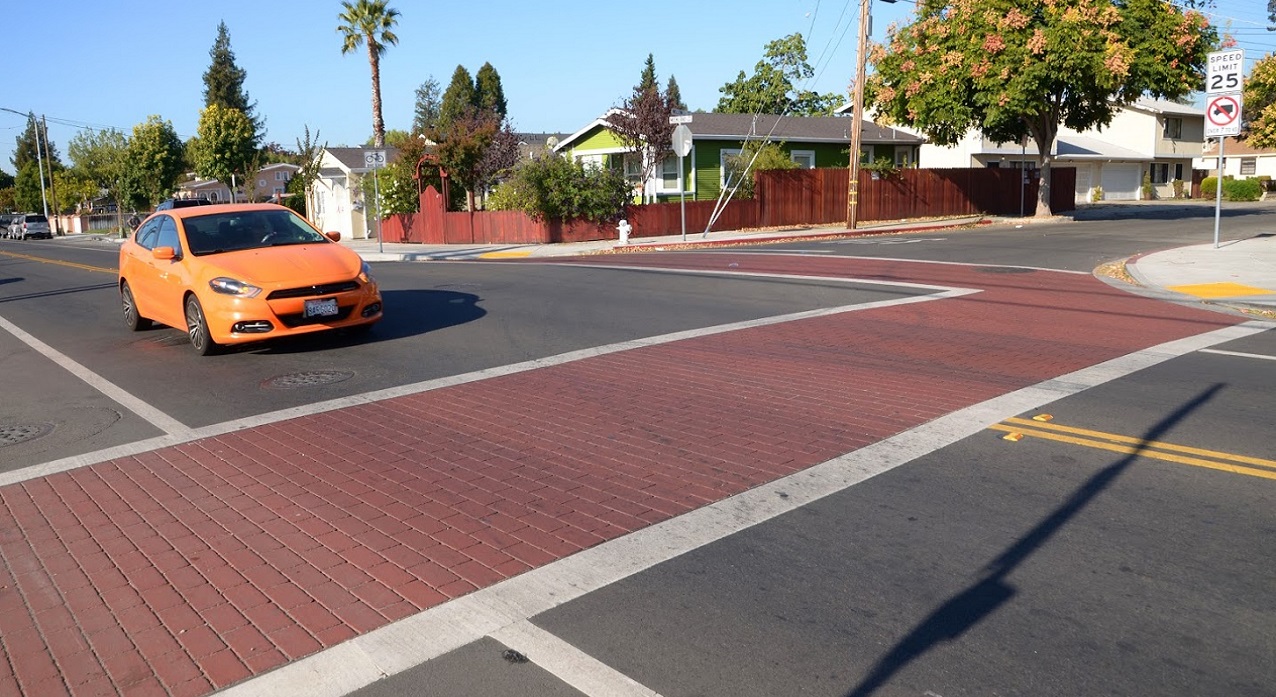 car approaching brick crosswalk