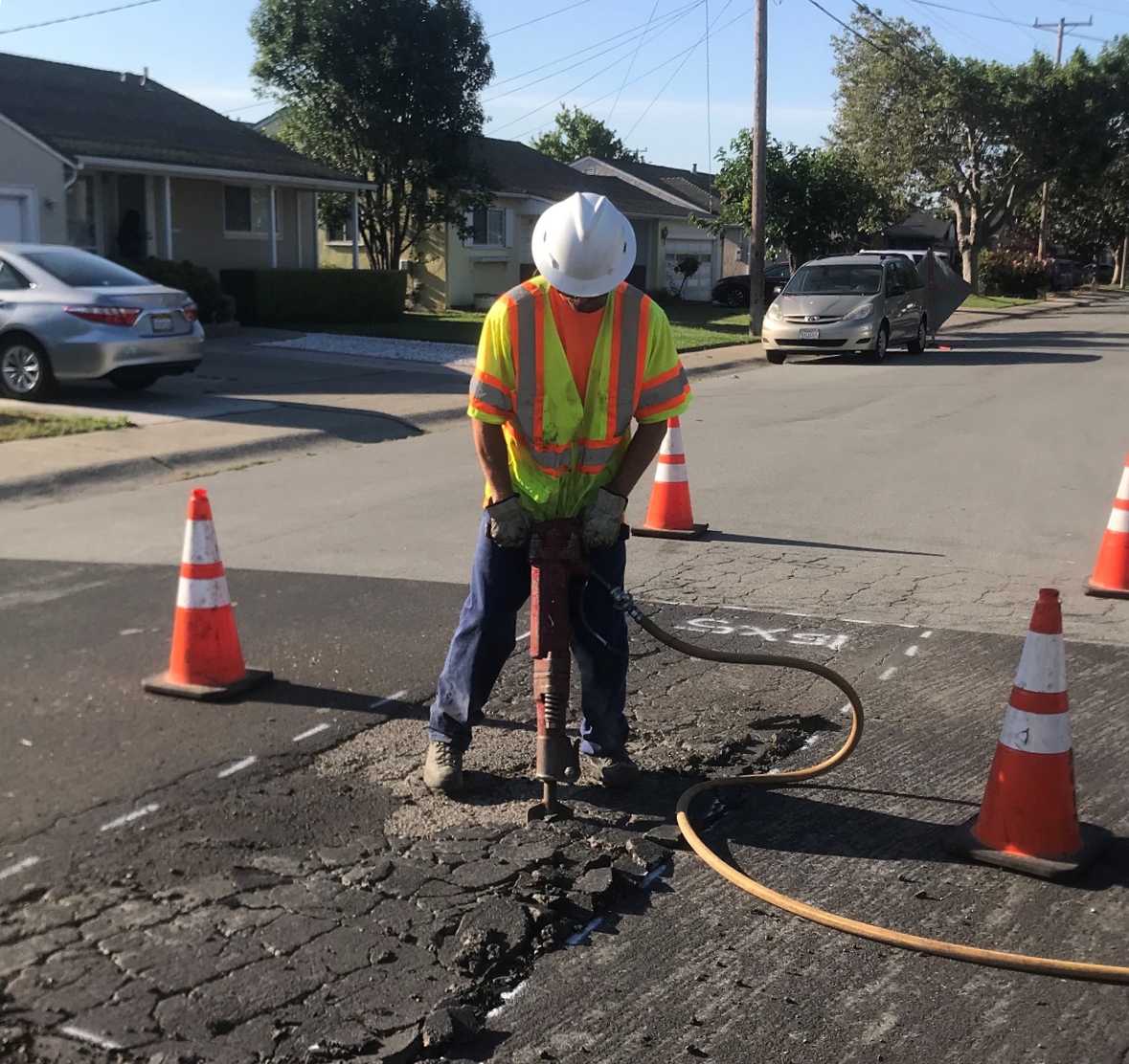 construction worker using jack hammer on street