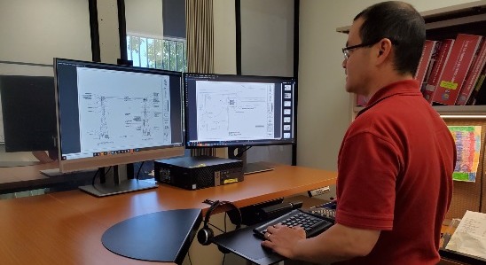 man at desk in front of 2 computer monitors